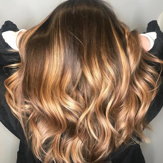 Model with long, wavy hair and caramel balayage, created using Wella Professionals.