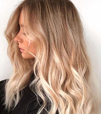 Side profile of woman with blonde color melt through hair, created using Wella Professionals.