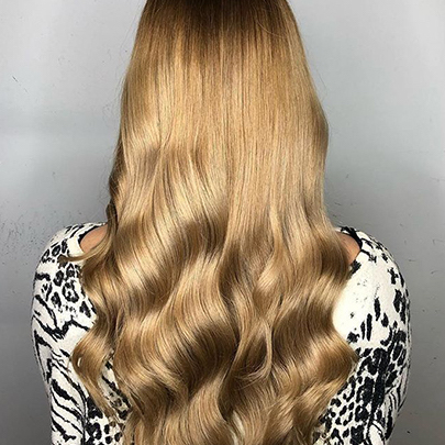Model mit langem, dunkelblondem Haar mit Karamelltönen, kreiert von Wella Professionals.