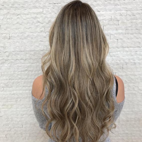 Model mit langem dunkelblondem Haar mit rauchigen Brauntönen, kreiert mit Wella Professionals.