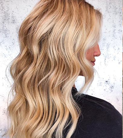Seitenprofil einer Frau mit langem, welligem, goldblondem Haar, das mit Wella Professionals kreiert wurde.