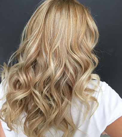 Hinterkopf einer Frau mit langem, Satin-goldblondem Haar, kreiert mit Wella Professionals.