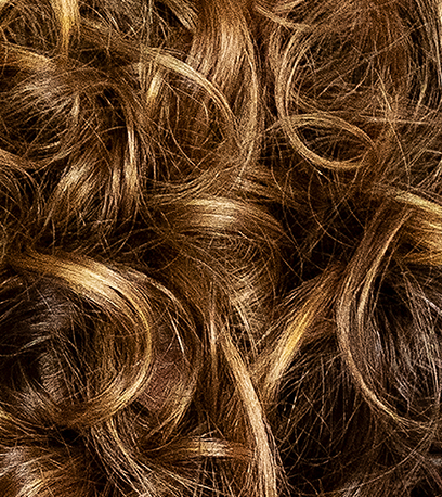 Close-up of golden brown, curly hair, created using Wella Professionals.
