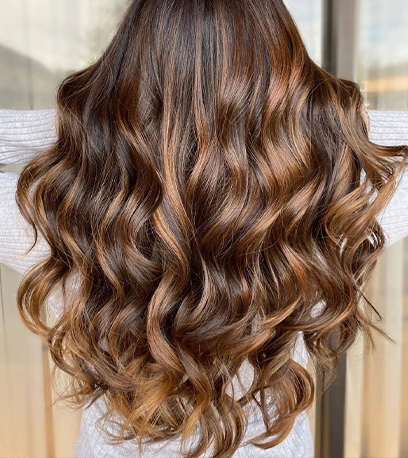 Back of woman’s head with long, golden mahogany brown, curly hair, created using Wella Professionals.