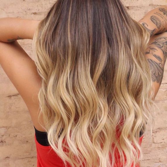 Frau mit gewelltem Haar und honigblonder Balayage, kreiert mit Wella Professionals.