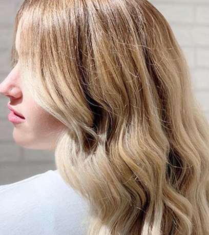 Model with wavy blonde hair and Illuminage, created using Wella Professionals.