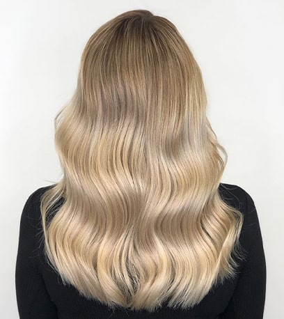 Photo of model with wavy blonde hair and Illuminage, created using Wella Professionals.