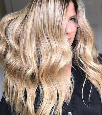 Woman with wavy, sandy blonde hair, created using Wella Professionals.