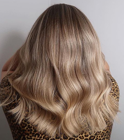 Back of woman’s head with wavy, sandy blonde hair, created using Wella Professionals.