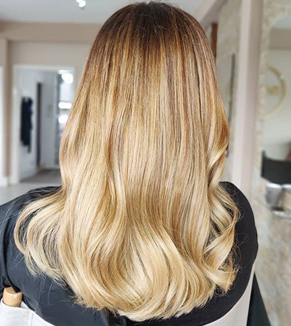 Back of woman’s head with long, loosely curled, sandy blonde hair, created using Wella Professionals.
