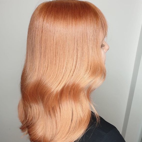 Der Hinterkopf einer Frau zeigt langes, pfirsichblondes Haar, das mit Wella Professionals kreiert wurde.
