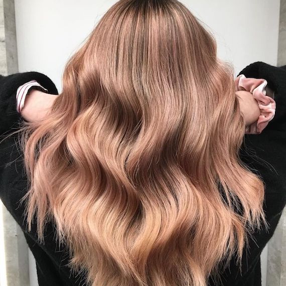 Model with long, wavy hair and subtle rose highlights, created using Wella Professionals.